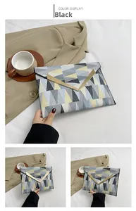 Detail of color-block envelope clutch with geometric pattern and gold V-shaped metal hardware