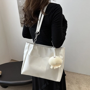 Elegante borsa tote bianca in pelle con tracolla a catena e ciondolo in peluche su modella