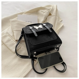 Close-up of black crossbody bag featuring silver butterfly buckle and protective bottom studs