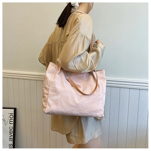 Détail du grand sac cabas rose pâle texturé avec une fine bandoulière en cuir marron