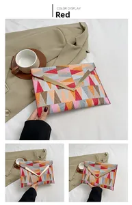 Detail view of fashion envelope clutch bag with red geometric patchwork and V-shaped gold trim