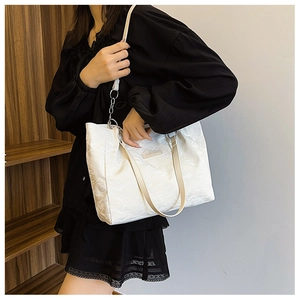 Détail d'un sac cabas blanc plissé avec poignées marron porté par un mannequin en robe