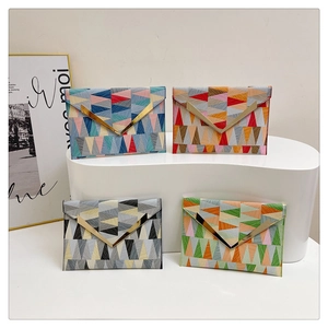 Detail of four envelope clutch bags with geometric triangle patchwork and gold V-shaped metal trim
