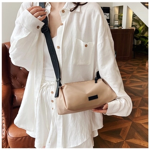 Detailed close-up of beige crossbody bag with adjustable wide black nylon shoulder strap