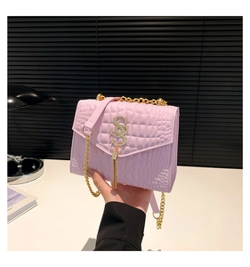 Détail du sac rose avec texture crocodile, logo en S doré et décoration de franges