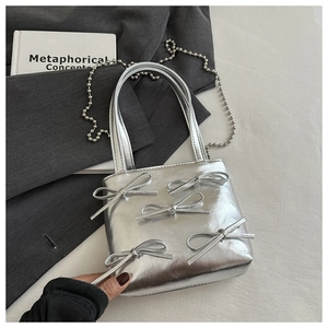 Detail of silver mirror mini bag featuring 3D bows and a delicate metal bead chain strap