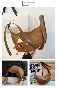 Detail of vintage brown crescent bag with fashion label and plush monster charm accessory