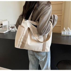Detailed side view of beige nylon tote bag with wide straps and spacious pockets