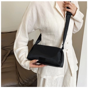 Detail of black minimalist crossbody bag with wide shoulder strap and textured fabric