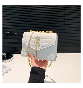 Détail du sac blanc à motif crocodile avec logo SS doré et bandoulière chaîne