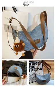 Detail of denim blue hobo bag with brown PU strap and plush monster charm accessory