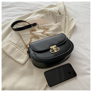 Detail of black faux leather crossbody bag featuring gold chain strap and metal lock