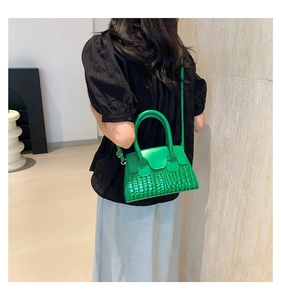 Dettaglio della borsa a tracolla verde brillante in pelle a coccodrillo su una modella