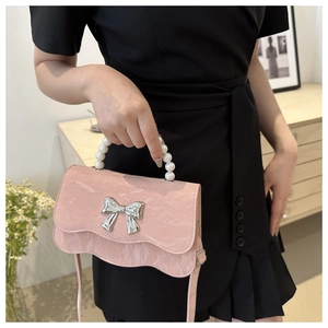 Detail of pink marble textured crossbody bag with pearl handle and silver bow accent