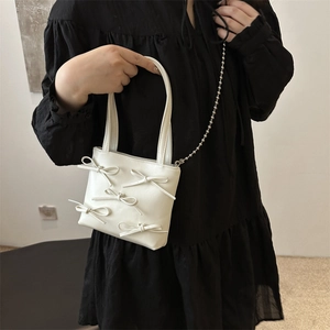 White faux leather shoulder bag with decorative bows and elegant silver bead chain strap
