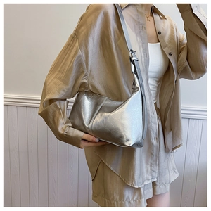 Close-up of metallic silver crescent bag with ruched texture and adjustable shoulder strap
