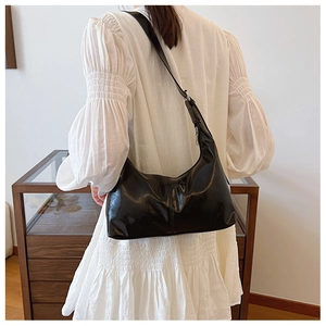 Detail view of a black glossy oil wax leather hobo bag with adjustable silver buckle