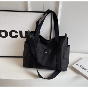 Dettaglio della borsa tote in tela nera con tracolla regolabile e tasche utili