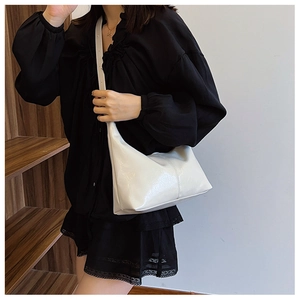 White glossy leather hobo bag with stitching detail shown worn as a shoulder bag
