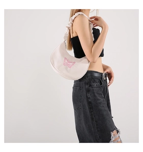 Close-up of cream crescent shoulder bag with pink butterfly embroidery and scrunchie strap