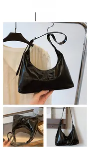 Detail view of the glossy black patent leather material and crescent shape of the tote bag
