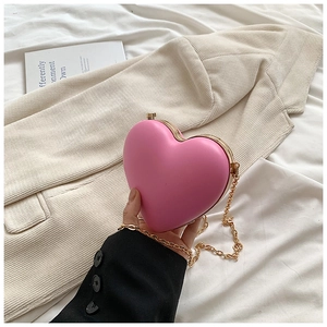 Detail einer rosafarbenen Herz-Handtasche mit goldener Kette und metallischen Goldkanten
