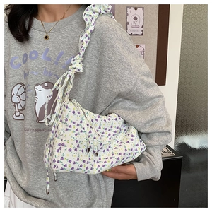 Detail view of floral canvas shoulder bag featuring ruffle straps and drawstring details
