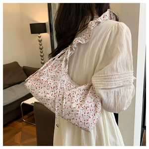Detailed view of floral pattern handbag featuring ruffle strap and drawstring sides