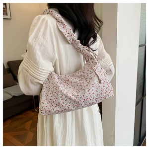 Detail of floral shoulder bag with red patterns and wide ruffled strap on a model