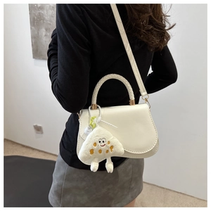 White woven handle crossbody bag with plush charm shown from a side view on a model