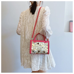Dettaglio della borsa rosa con paillettes metalliche indossata su un abito bianco