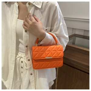 Close-up of vibrant orange quilted crossbody bag with gold hardware and woven handle