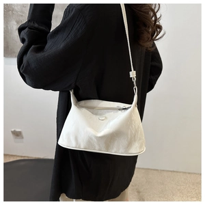 Détail d'un sac à bandoulière en cuir verni blanc avec texture froissée et boucle argentée