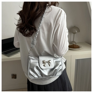 Sac bandoulière argenté métallisé avec boucle nœud et design plissé sur un modèle