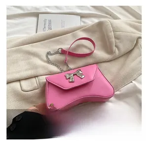 Detail of pink PU leather handbag featuring a silver metal bow buckle and asymmetric base