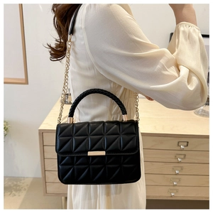 Detailed view of black quilted crossbody bag with gold chain strap and woven handle