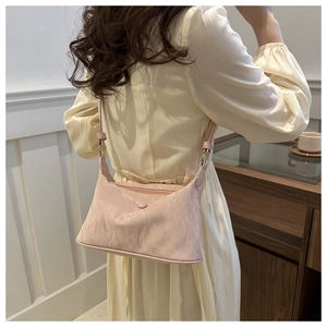 Gros plan du sac bandoulière rose clair en similicuir à texture marbrée dans un café