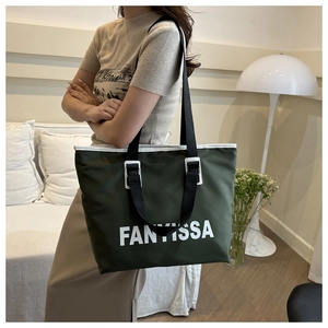 Detail of waterproof nylon tote bag in deep green with durable black straps and metal buckles