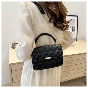 Detailed view of black quilted crossbody bag with woven handle and gold hardware