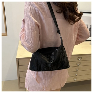 Gros plan d'un sac hobo noir plissé au design épuré en forme de croissant incurvé