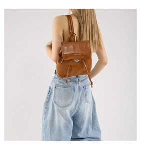 Rear view of model wearing a stylish brown PU leather bucket backpack with metal lock