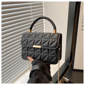 Detail of black quilted crossbody bag with gold buckle and woven handle grip
