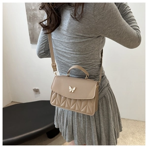 Chic beige crossbody bag featuring embroidered butterfly clasp worn by female model