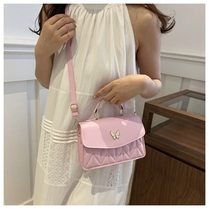 Detail of soft pink crossbody bag featuring white butterfly metal clasp and V-quilted texture