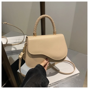 Detail of beige crossbody bag with woven handle and wavy flap design on leather texture