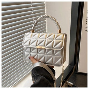 Close-up of silver quilted PU leather bag with gold buckle and woven handle detail
