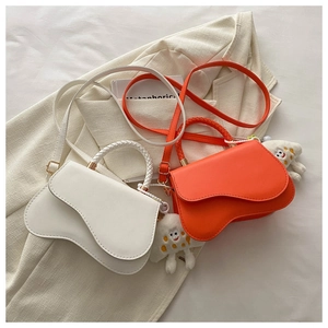 Detailed view of woven handles and wave-flap crossbody bags with plush charms on a blazer