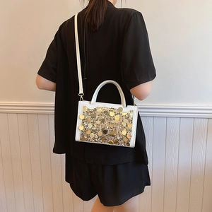Elegante borsa a tracolla bianca con paillettes dorate e manico rotondo indossata da modella