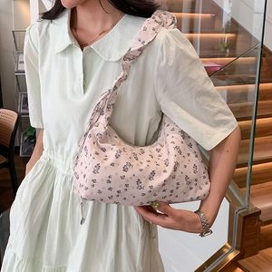 Pink floral tote bag with ruffled strap worn by model in a stylish indoor setting