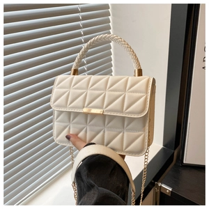 Detail of white quilted leather handbag with gold clasp and woven handle texture